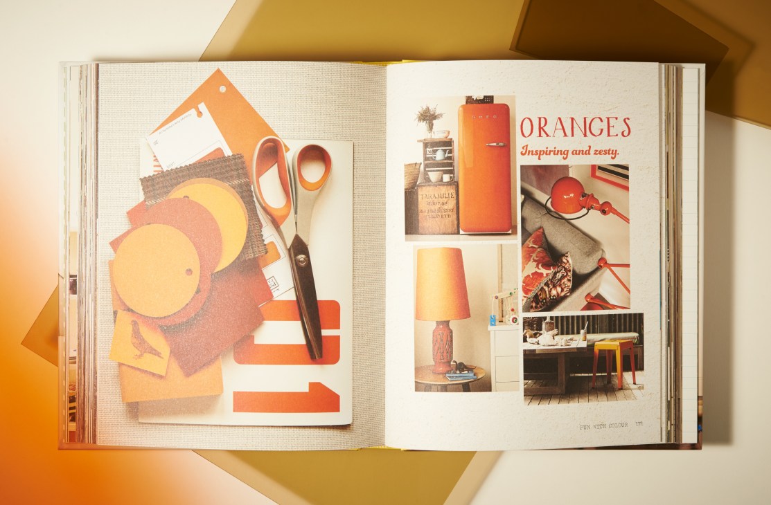 An open book spread showing interior design inspiration with orange-themed styling and home décor elements.