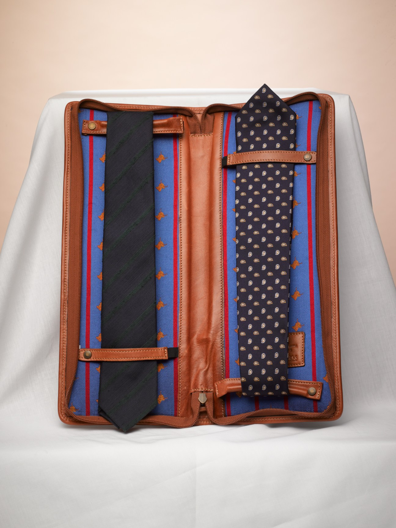 Moore&Giles leather tie case open displaying patterned ties and interior compartments.