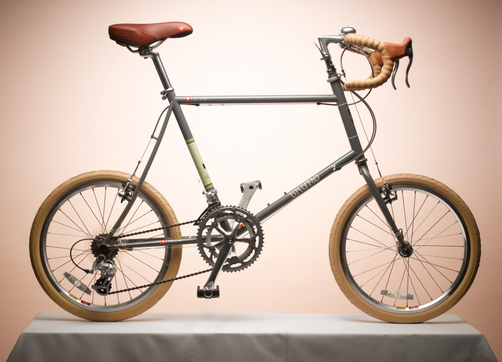 Japanese-made, Swiss-designed Bruno mini-velo bike with tan tires and leather accents displayed on a pedestal.