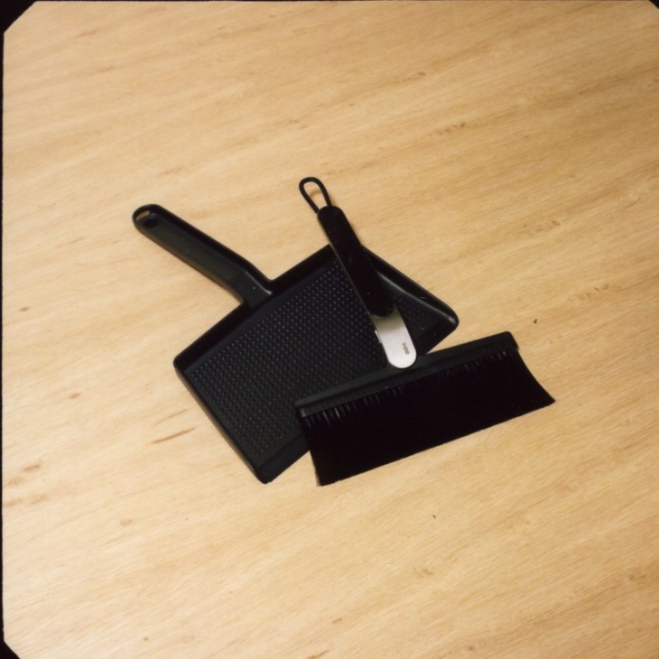 Vipp broom and dustpan set in black aluminum with stainless steel brush on light wood surface.