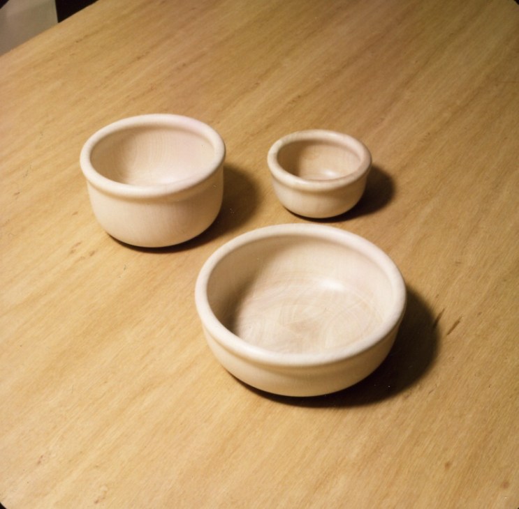 Three wooden bowls in natural finish arranged on a light wood surface, designed by Anderssen & Voll for Bowling.