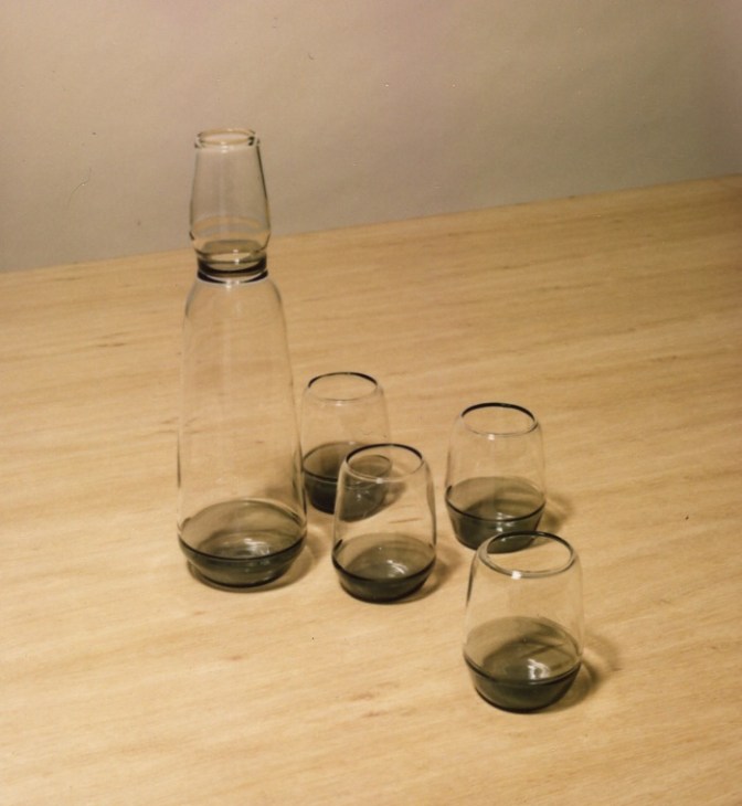 Grigia glassware set by Chiara Onida featuring a carafe and glasses with grey incalmo details on a wooden surface.