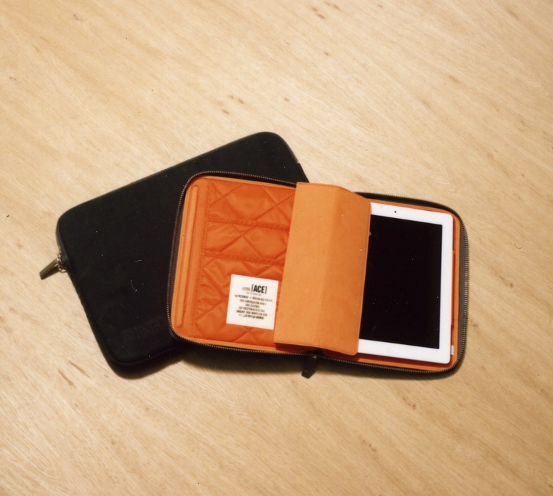 Incase x Ace Hotel iPad 2 case in black waxed cotton with orange quilted interior holding a tablet.
