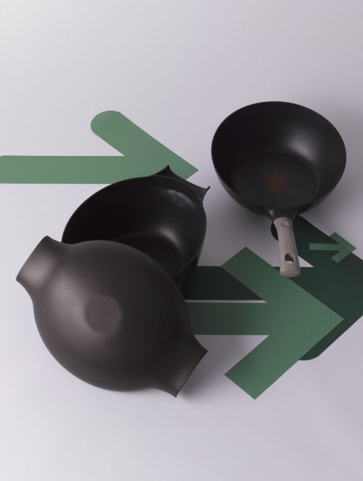 Tefal Natura non-stick cookware range including a black cocotte and frying pan with green geometric shapes.