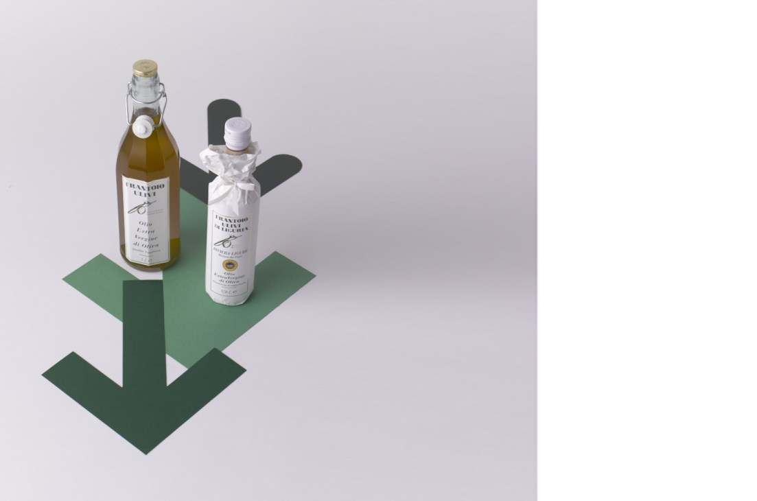 Frantoio Ulivi Di Liguria extra virgin olive oil bottles displayed on a geometric green platform.