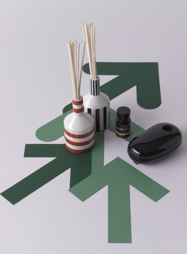 Serene House scent diffusers with striped ceramic vessel, reed diffuser, amber bottle and black atomizer on green star-shaped platform.
