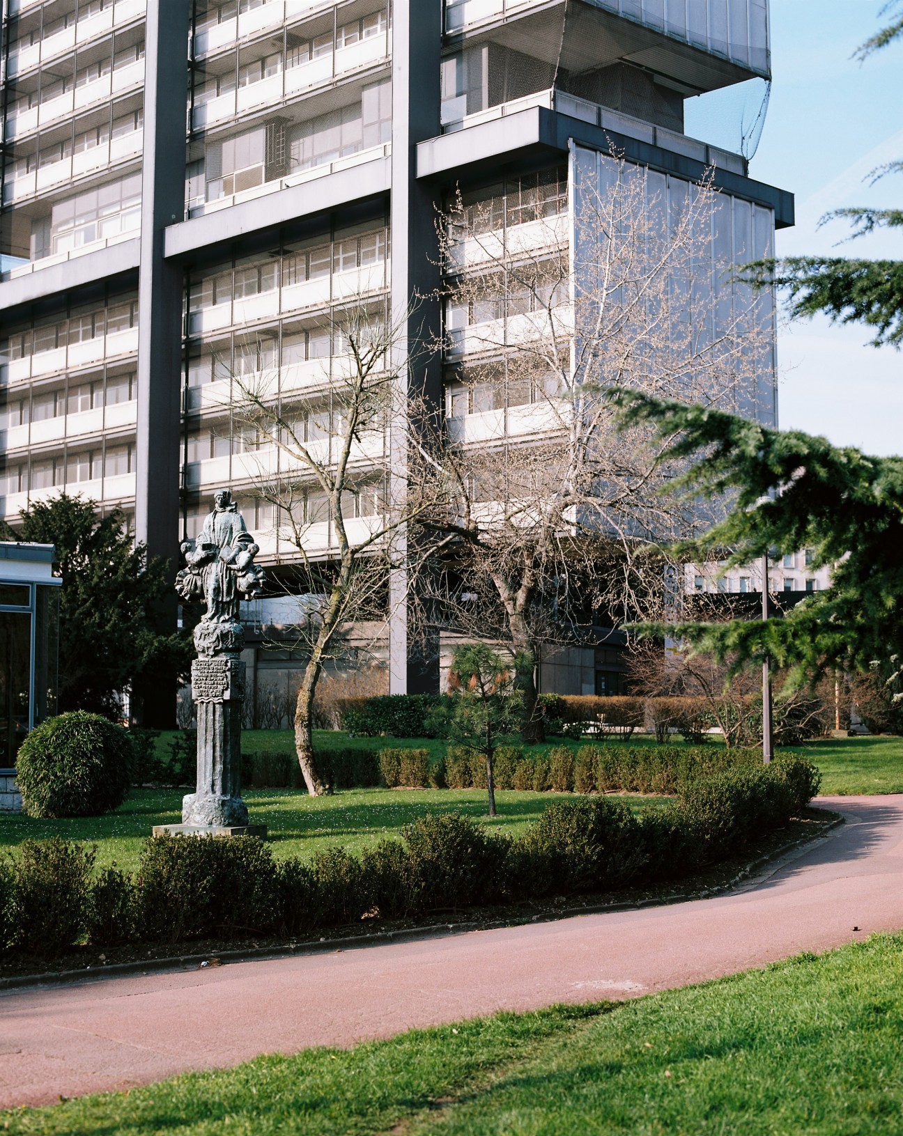 Modernist residential building with manicured gardens and statue in foreground at Cité Internationale Universitaire de Paris.