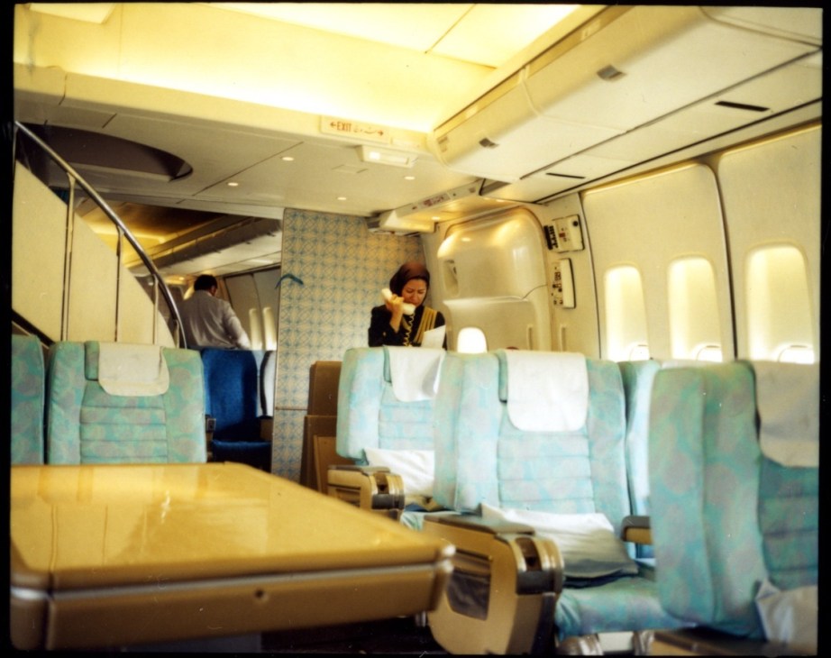 IranAir business-class cabin with blue and tan geometric patterned seats and crew members.