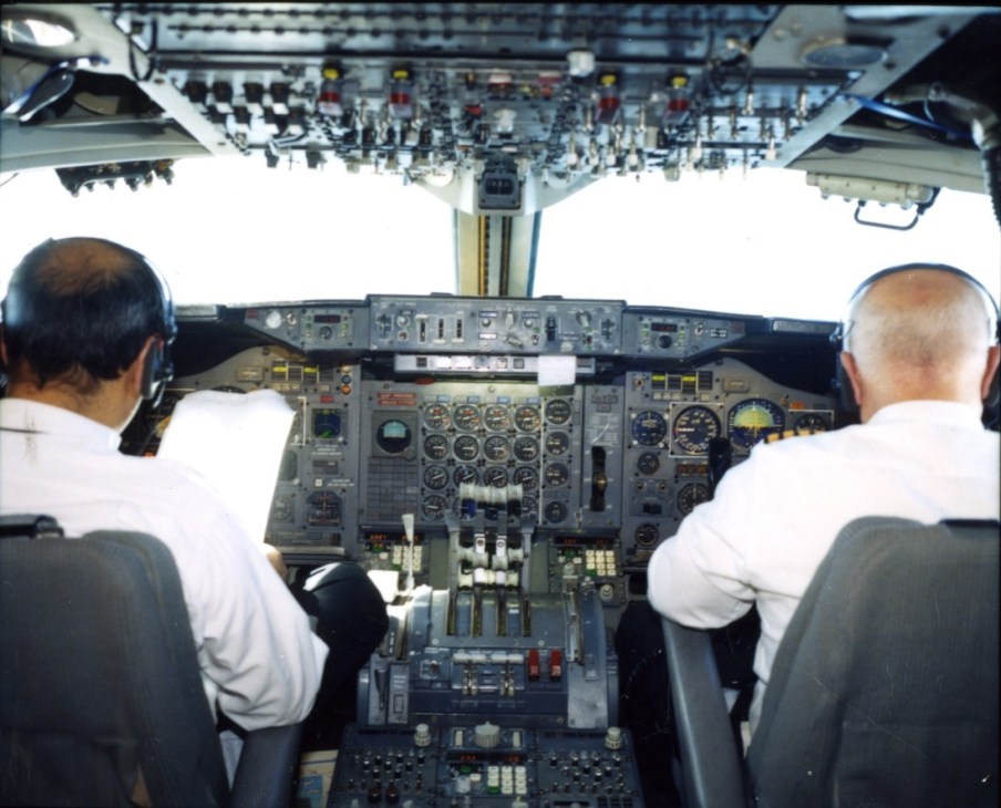 Two pilots in white shirts at the controls of a Boeing 747 cockpit during flight.