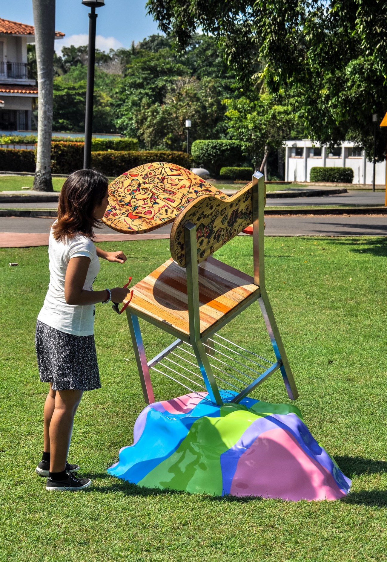 Student adjusting colorful artwork on display structure in ISA campus courtyard.