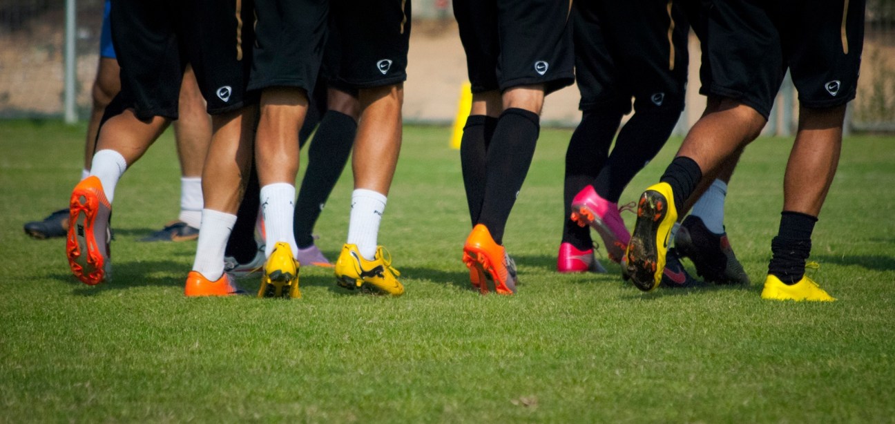 Close-up of soccer players' feet and colorful cleats on grass during a match.