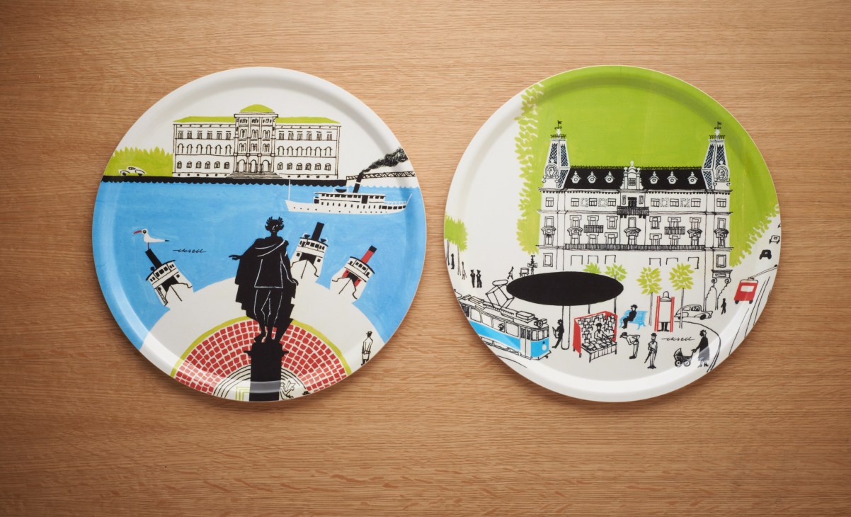Two ceramic trays with illustrated designs by Olle Eksell featuring architectural and street scenes on a wooden surface.