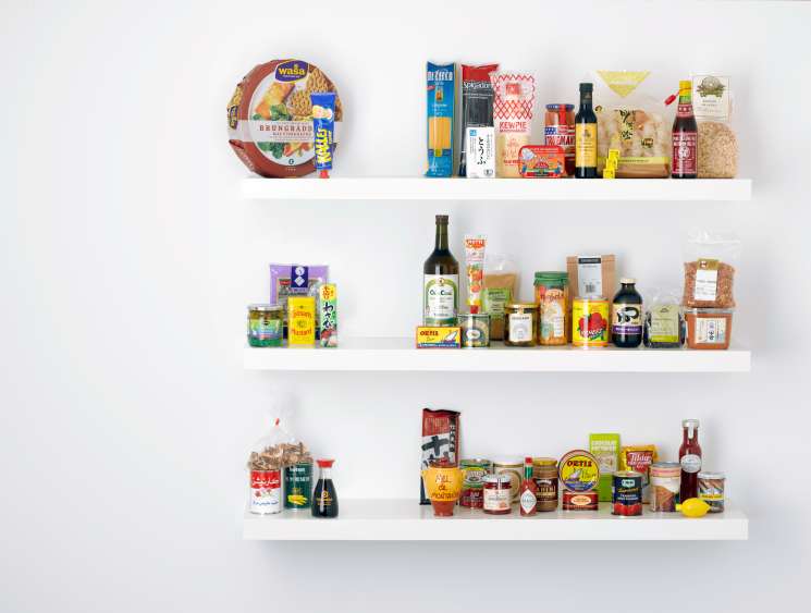 Four white shelves stocked with 50 numbered pantry staples including pasta, oils, sauces, and preserved foods.