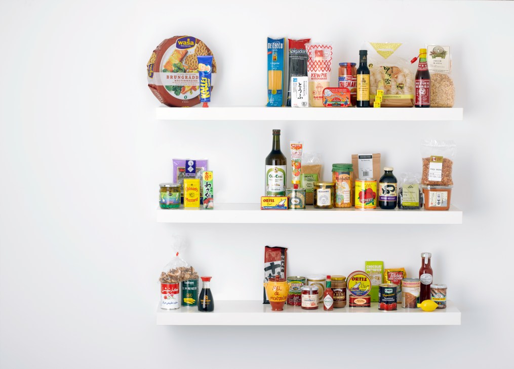 Four white shelves stocked with 50 numbered pantry staples including pasta, oils, sauces, and preserved foods.