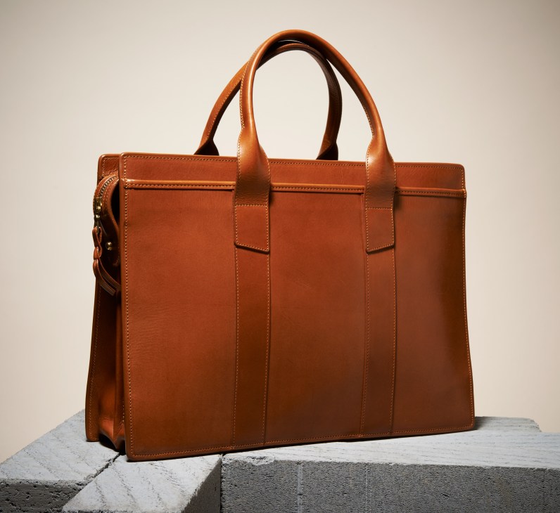 Tan vegetable-tanned leather briefcase with dual handles and shoulder strap attachment by Frank Clegg Leatherworks.