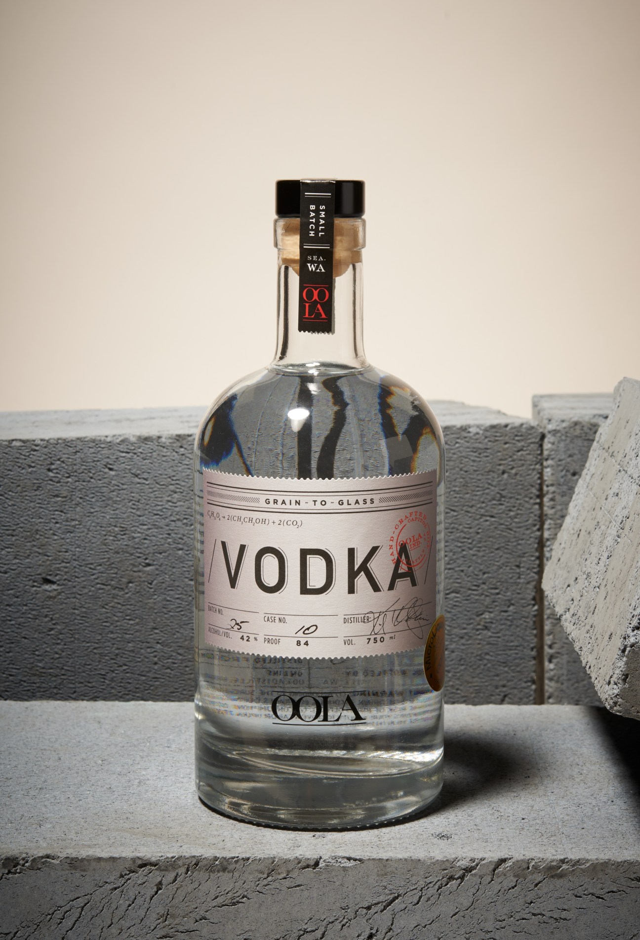 Oola Distillery vodka bottle with hand-etched label displayed on concrete surface.