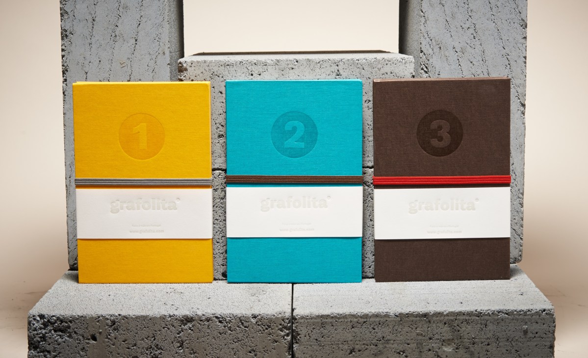 Three colorful Grafolita notebooks with numbered covers displayed on concrete blocks.