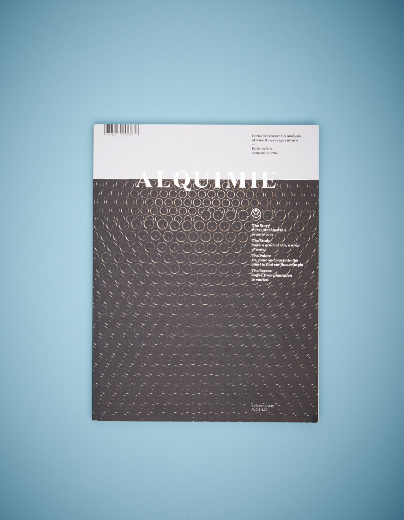 Alquimie drinks quarterly magazine cover featuring textured dark design against light blue background.