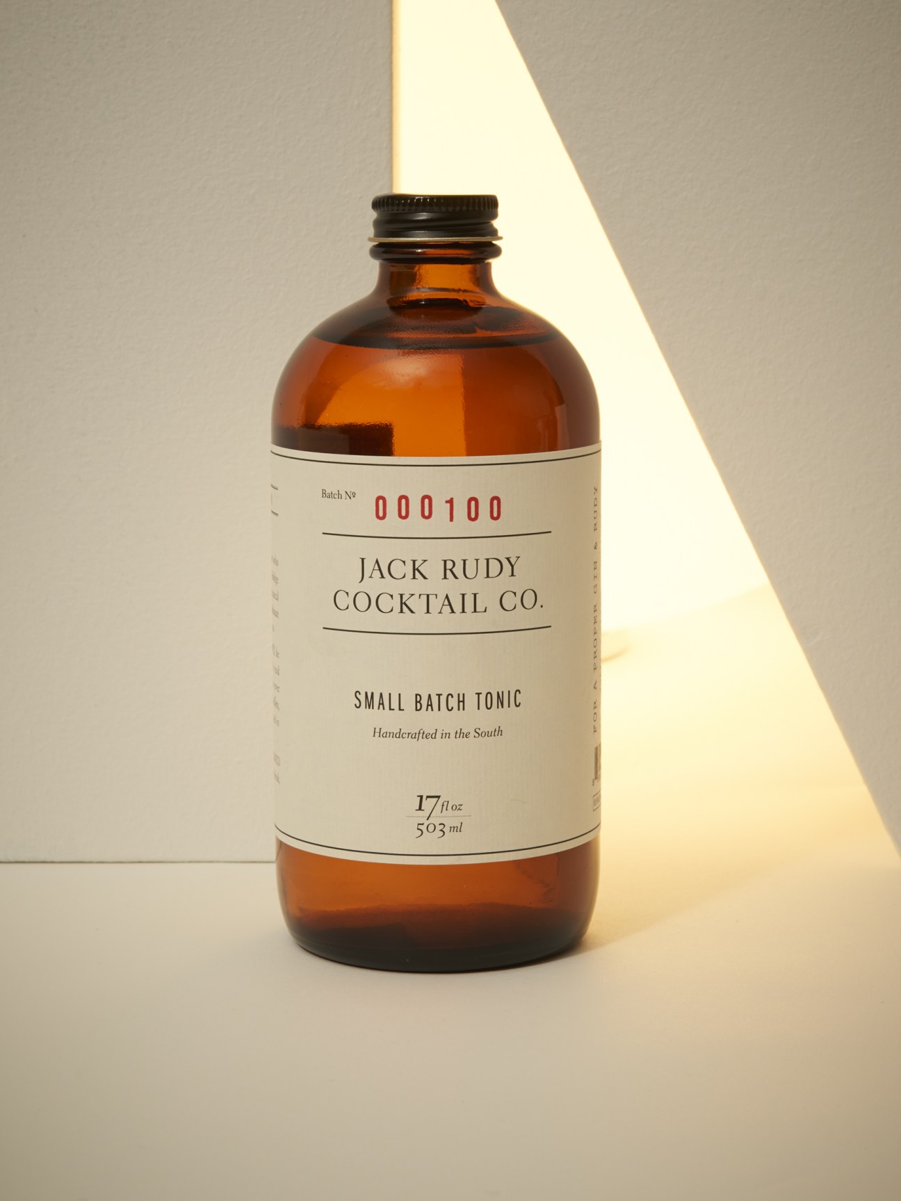 Jack Rudy Cocktail Co small batch tonic bottle with amber glass and cream label.