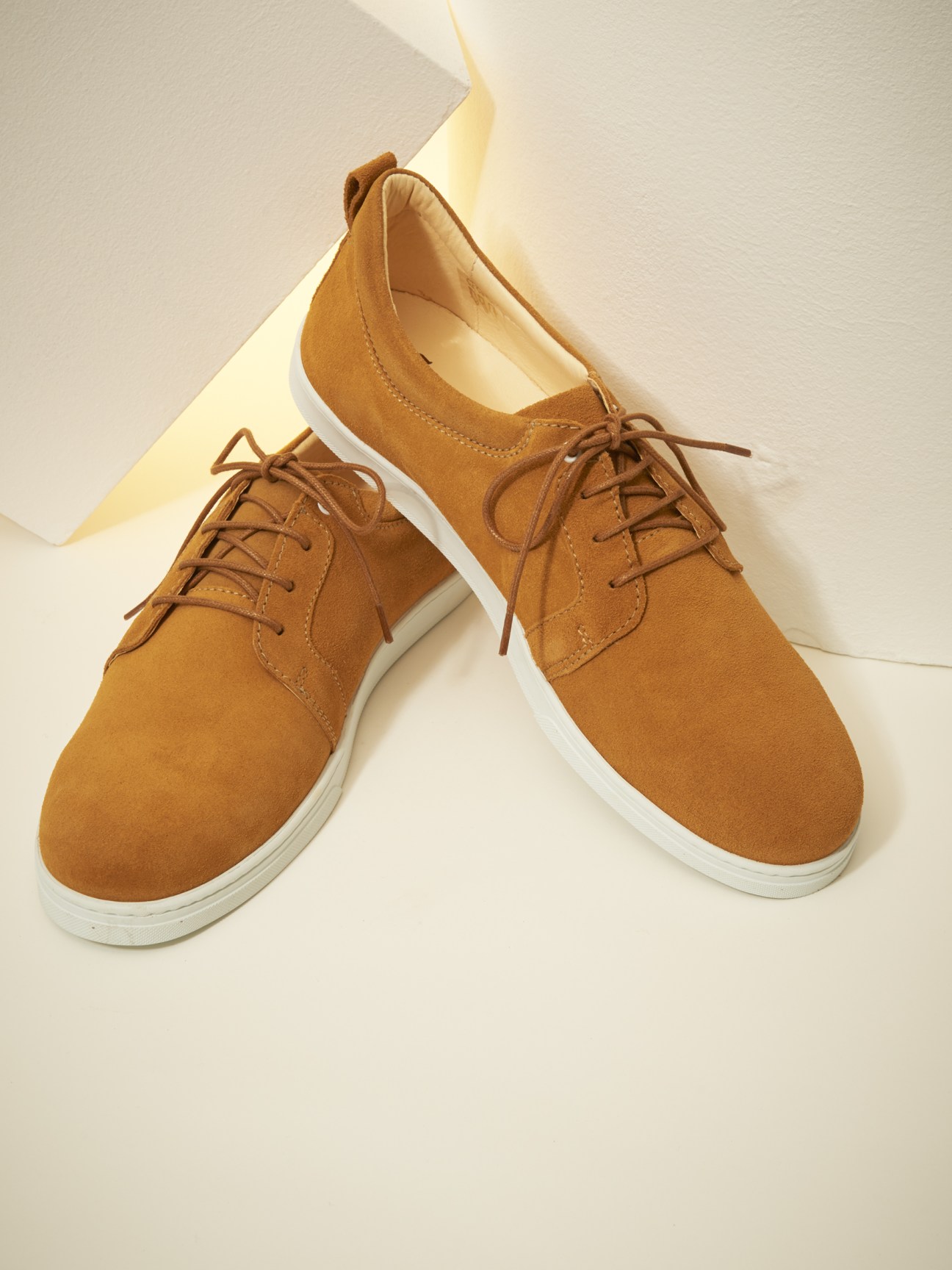 Pair of tan lace-up shoes with white soles by Ekn, displayed on a neutral background.