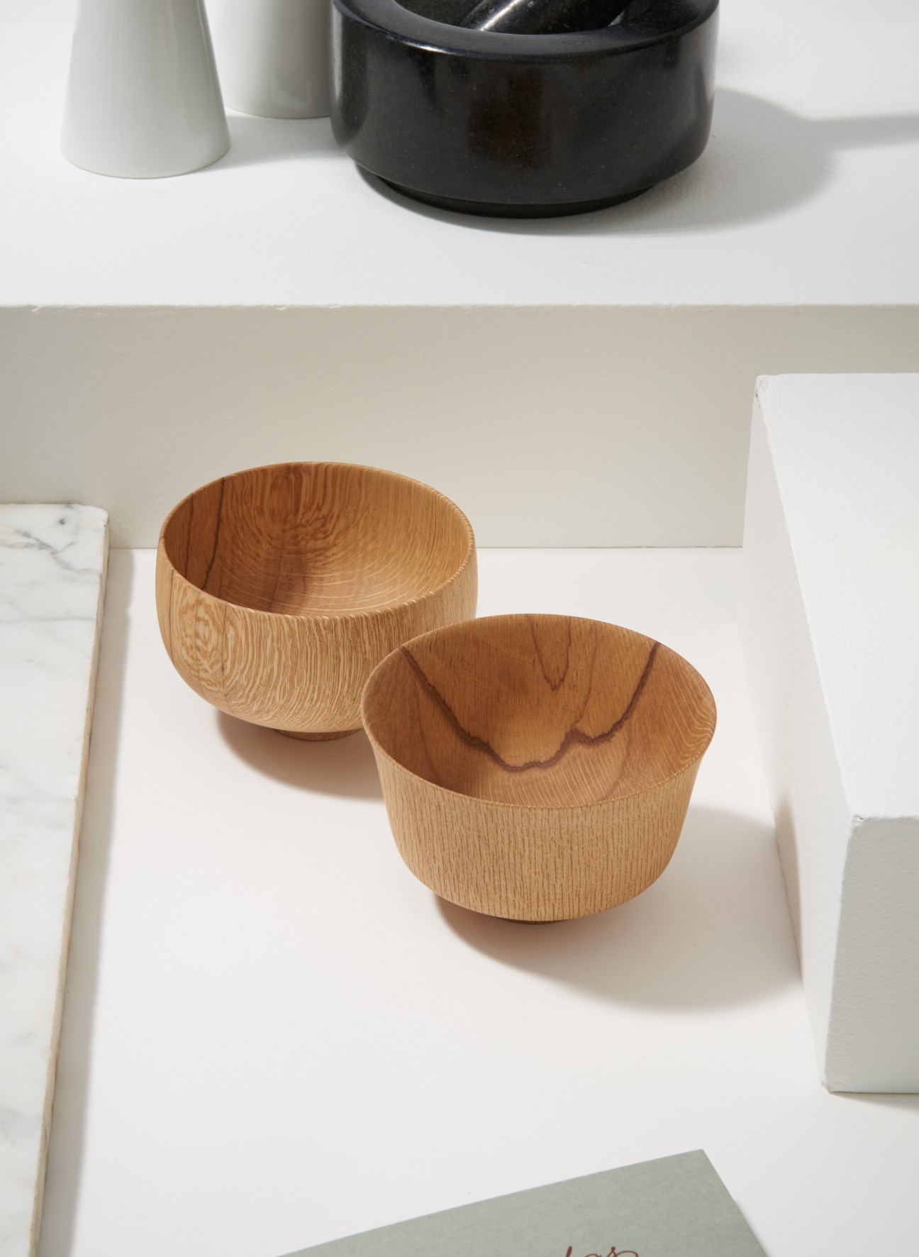 Two light wooden bowls with natural grain texture displayed on a white surface.