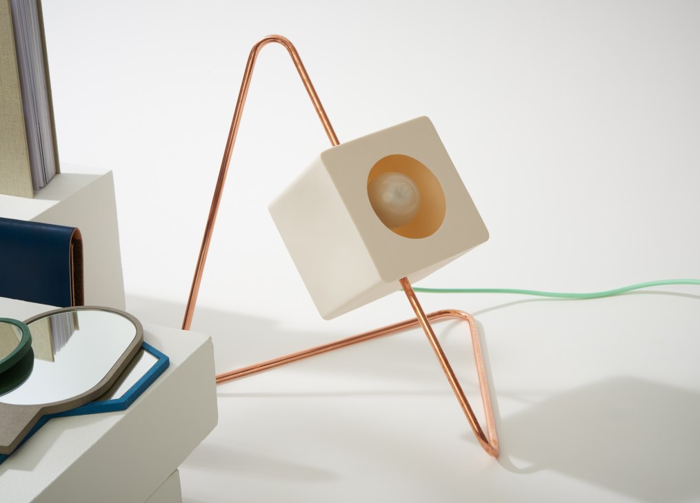 Designlump's Focal Point lamp with triangular copper frame, cream porcelain cube, and green power cord on white surface.