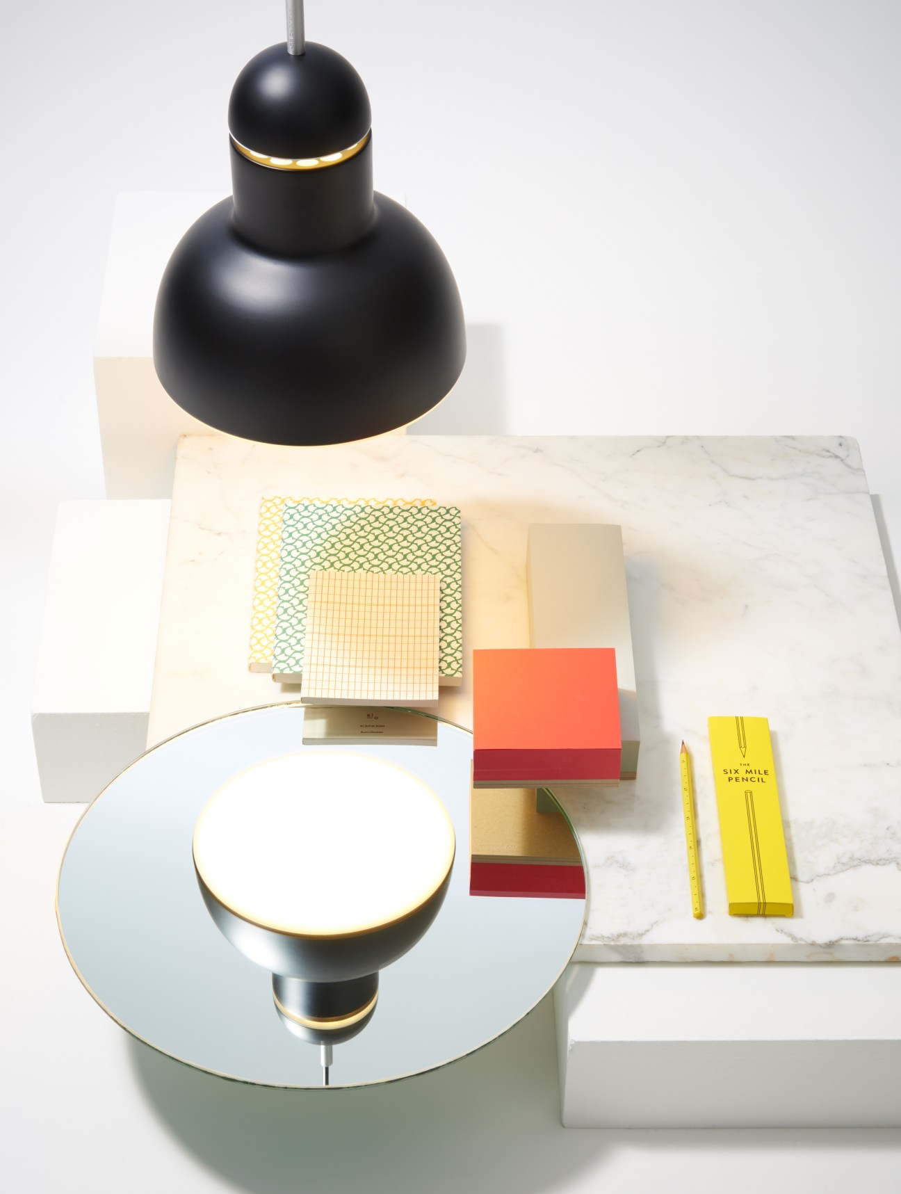 Styled flat lay with Anglepoise pendant lamp, Ola stationery, Ito Bindery memo pad, and Lyon & Lyon Six Mile Pencil on marble surface.