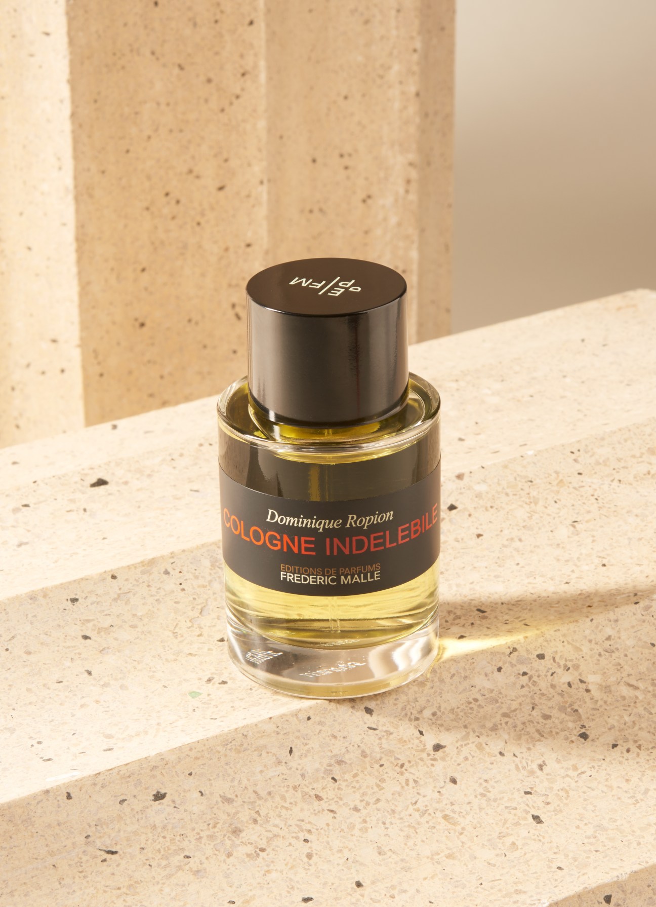 Frédéric Malle Cologne Indélébile perfume bottle with black cap and label on terrazzo surface.