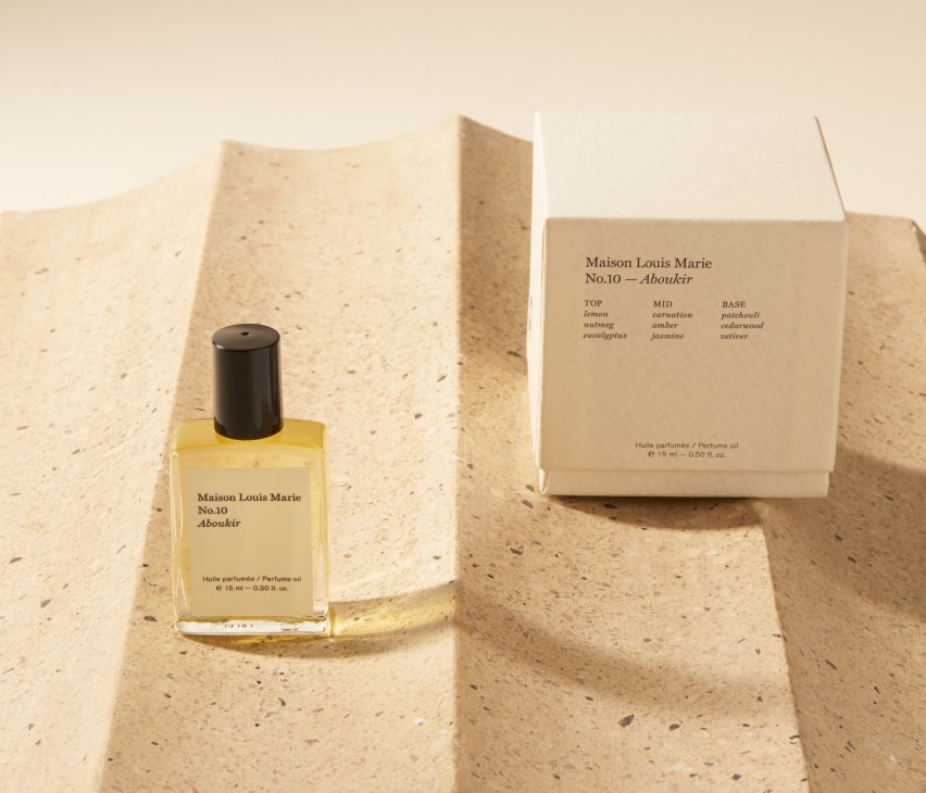 Maison Louis Marie No.10 Aboukir fragrance bottle with yellow oil and kraft paper packaging on textured surface.