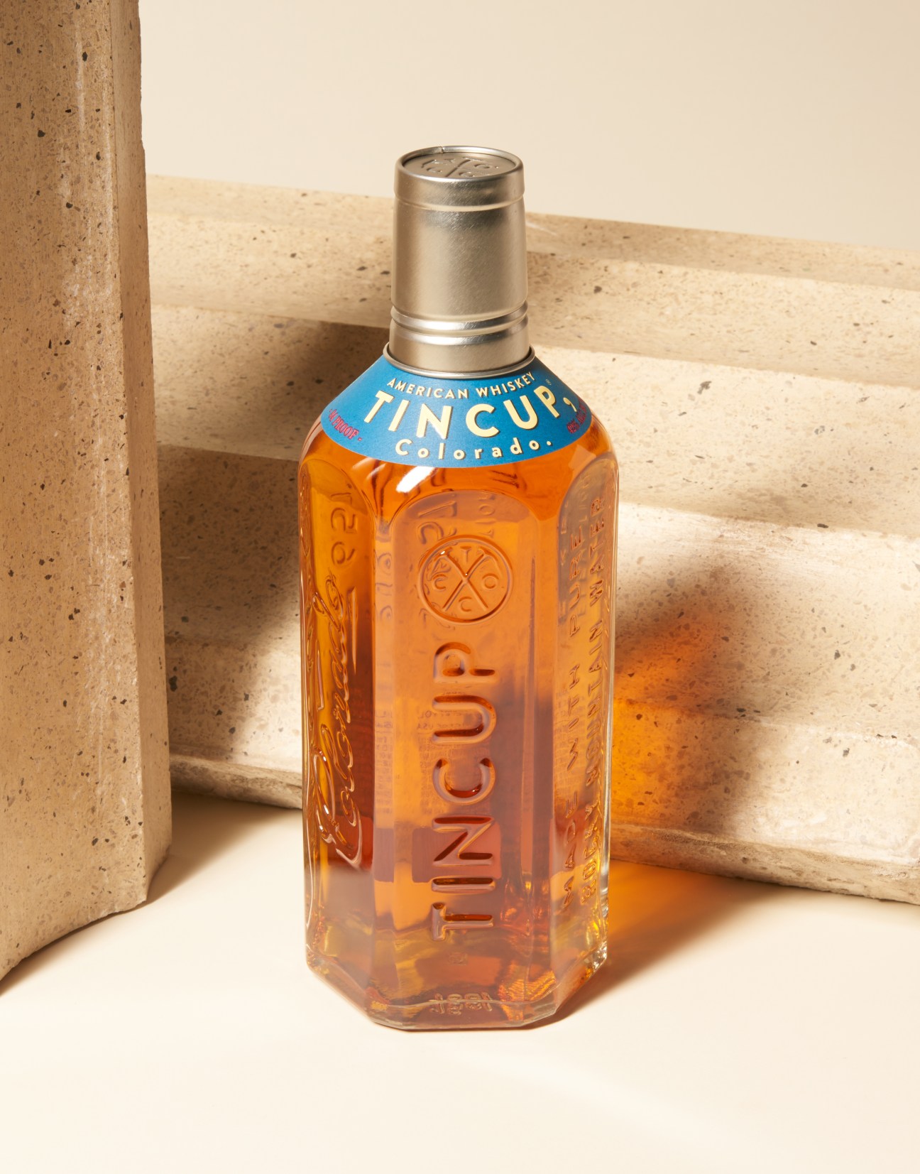 Tincup American Whiskey bottle with metal cap displayed on concrete surface.