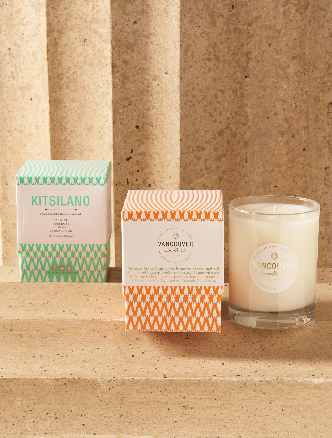 Vancouver Candle Co scented candles displayed with patterned packaging boxes against a cork background.