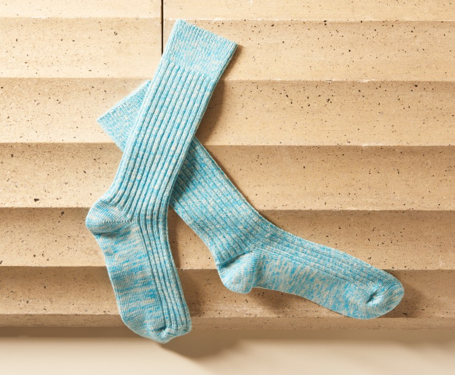Pair of blue and grey ribbed Italian cotton socks arranged on a cork tile background.