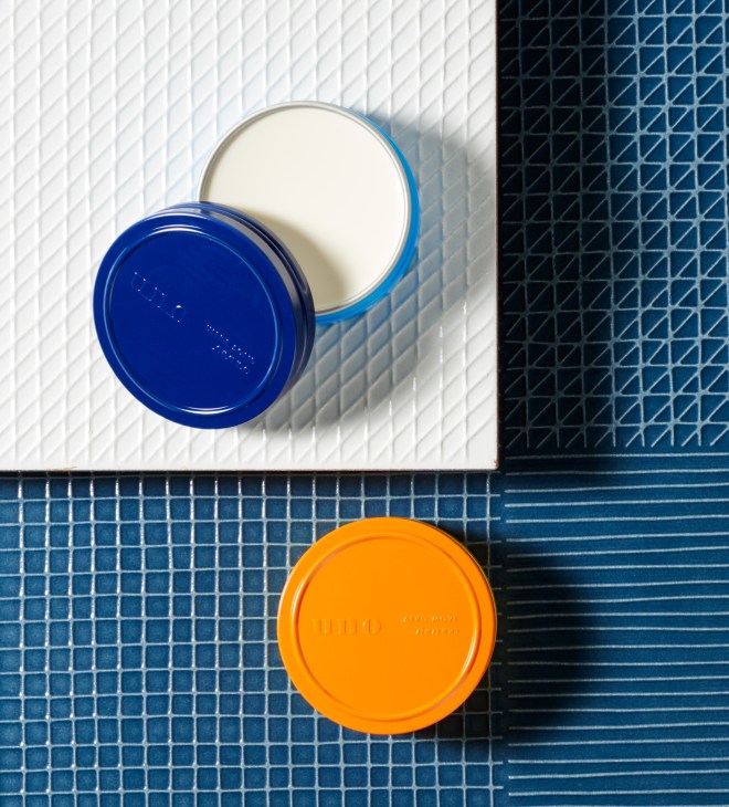 Uno hair wax by Shiseido in blue and orange containers on patterned tile background.
