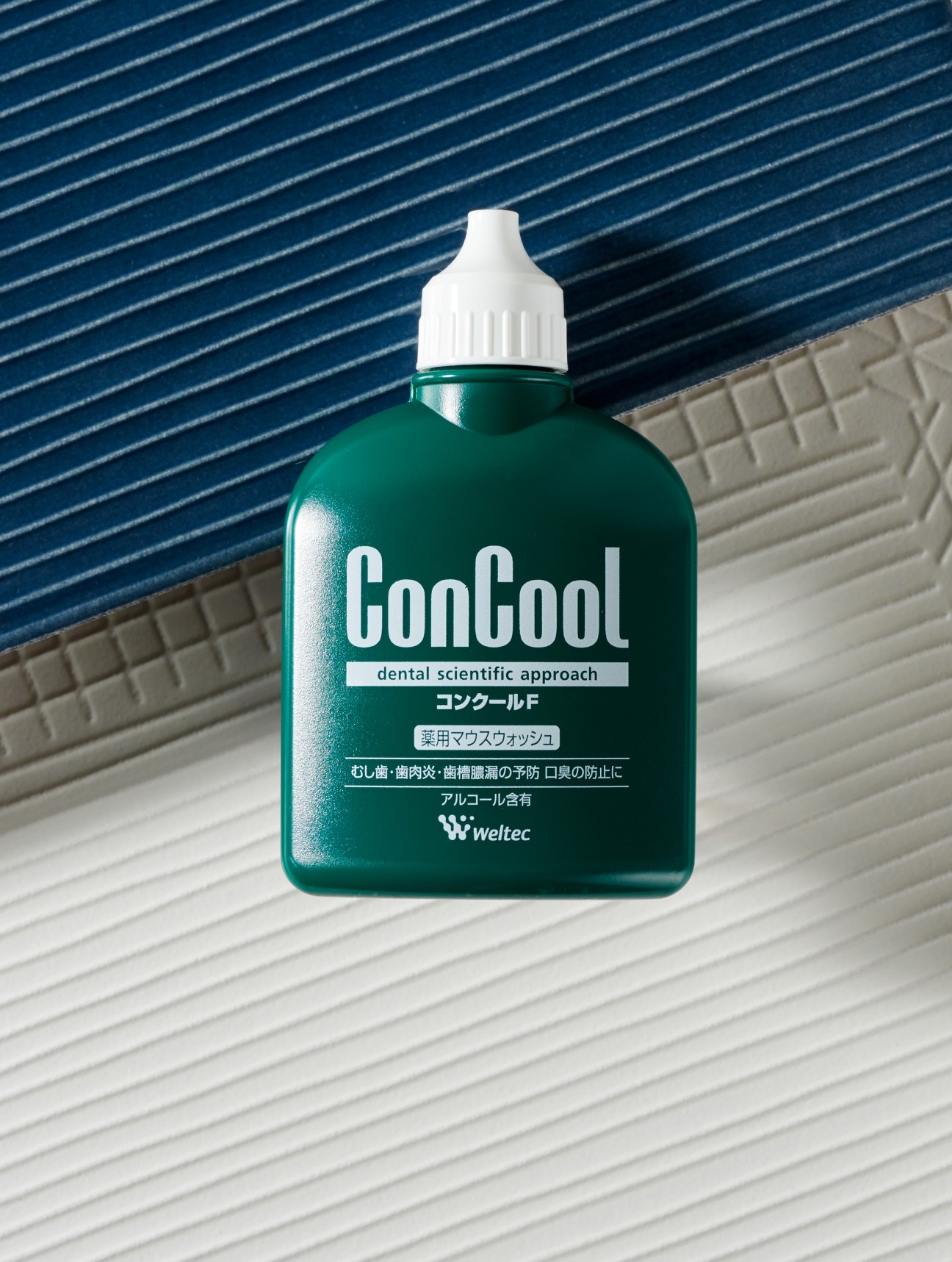 ConCool F mouthwash bottle by Weltec with green container and white cap on blue and white tiled background.