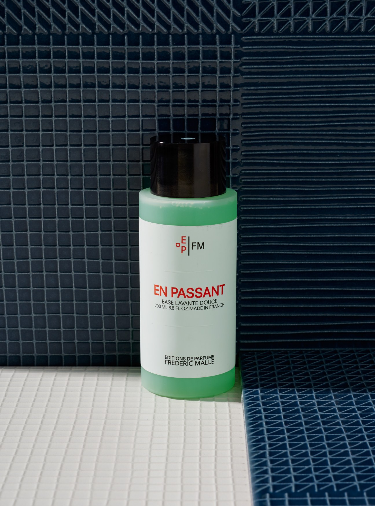 Frederic Malle En Passant shower gel bottle with green and white label on tiled bathroom background.
