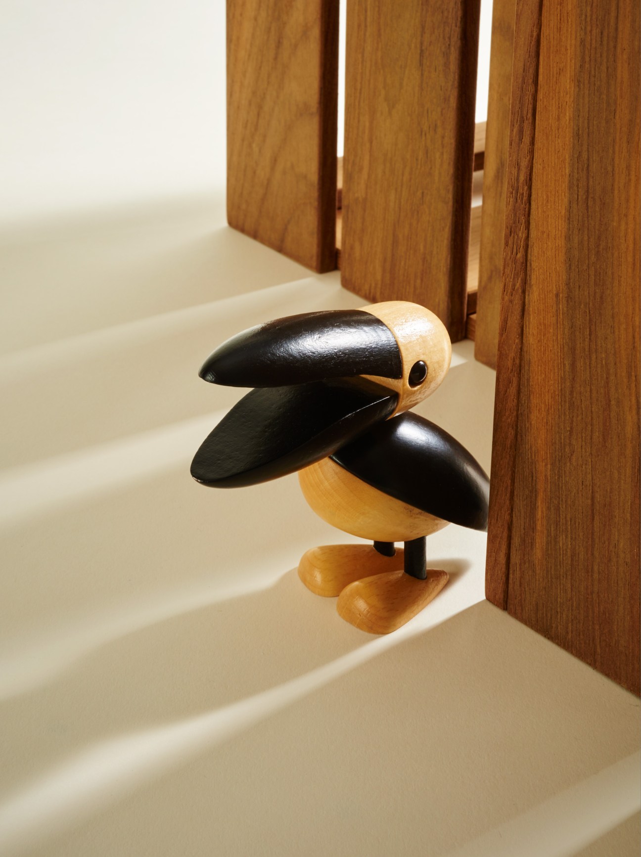 Black and natural wood wooden pelican toy by Lucie Kaas with articulated beak and legs.