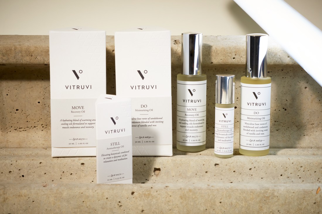 Vitruvi aromatherapy oils and sprays arranged on a concrete surface with packaging boxes.