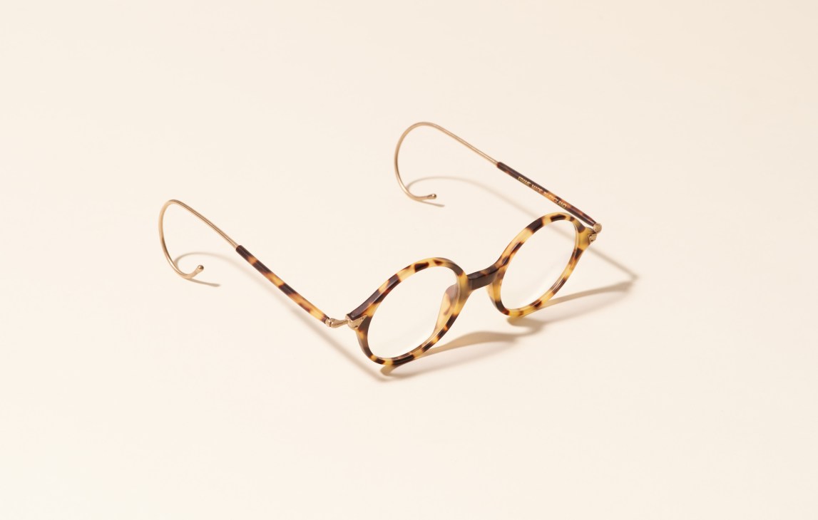 Tortoiseshell and rose gold-toned eyeglasses with round frames on a cream background.
