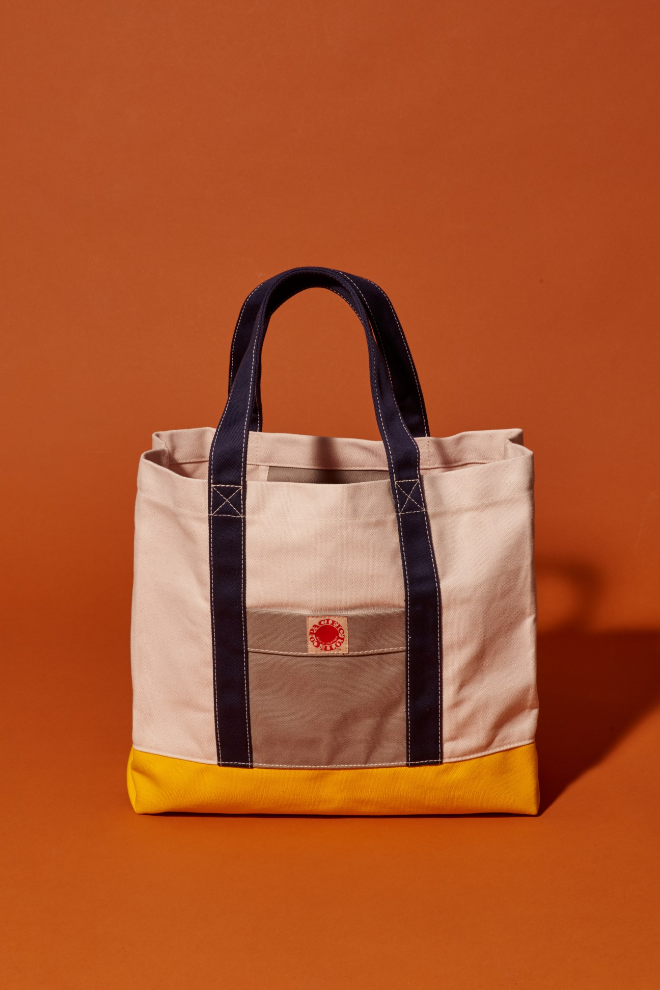 Pacific Tote Company canvas tote bag with cream, navy and yellow colorblocking and dark handles.