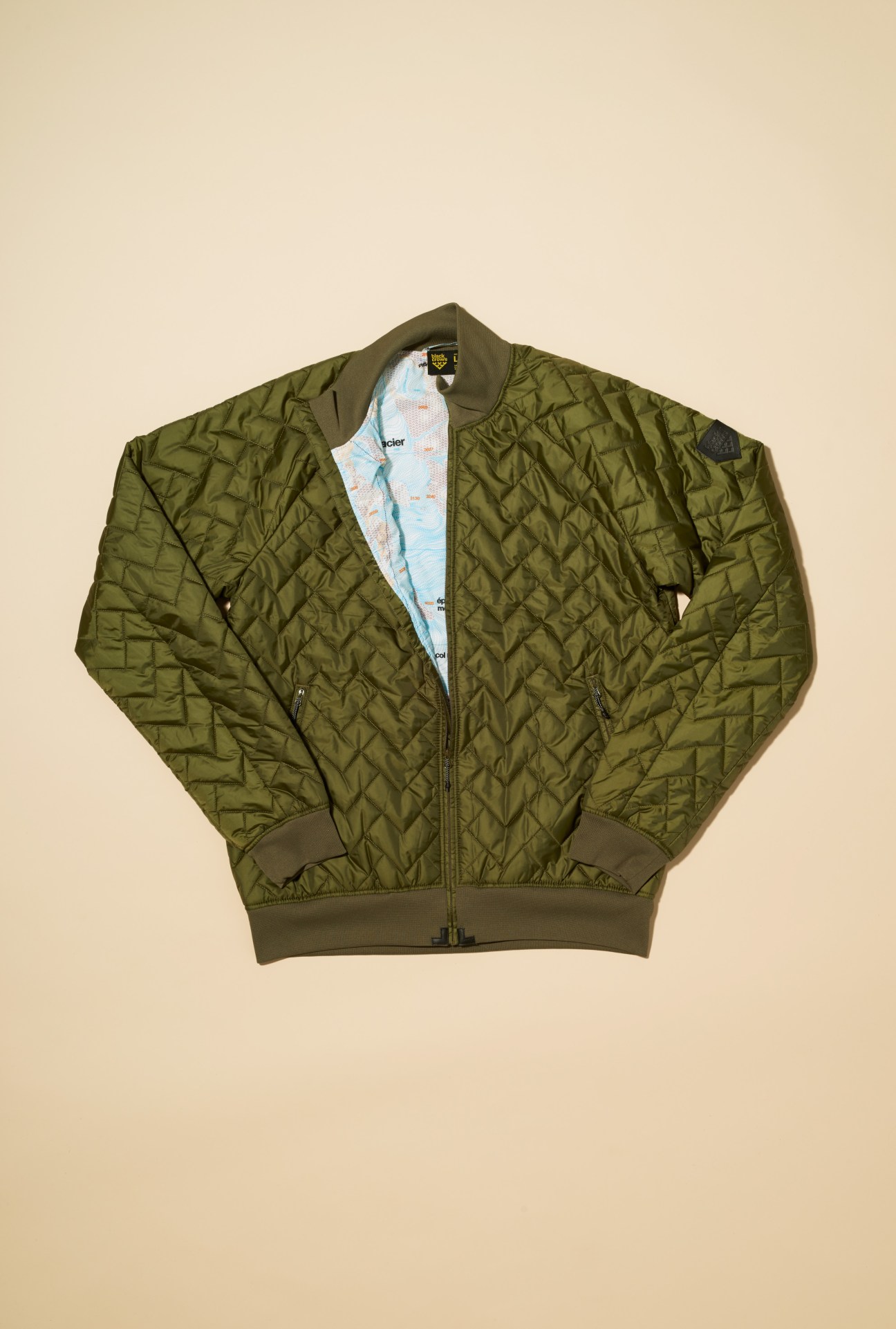 Olive green quilted PrimaLoft jacket by Black Crows with blue printed lining visible at the collar.