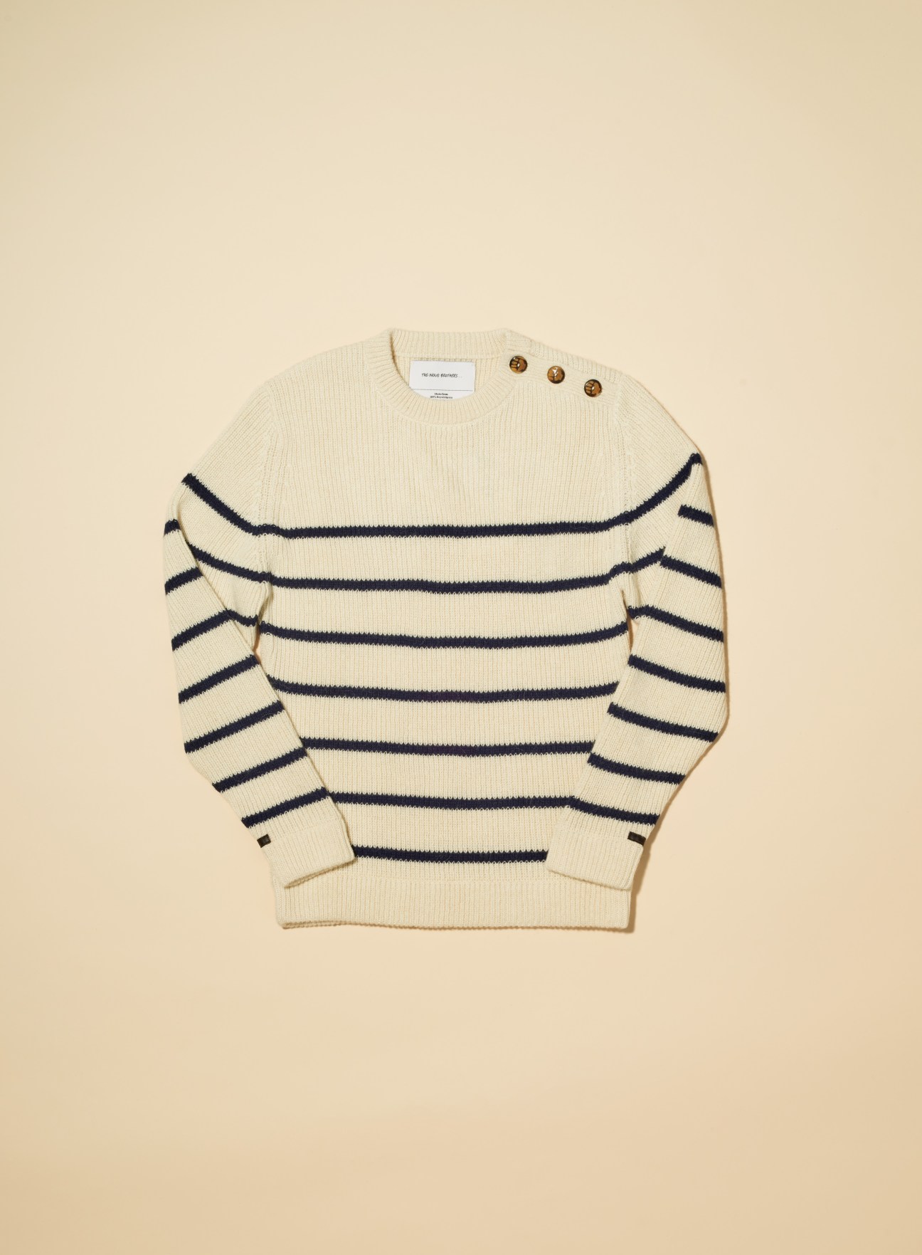 Cream wool jumper with navy horizontal stripes and wooden button details at shoulder.