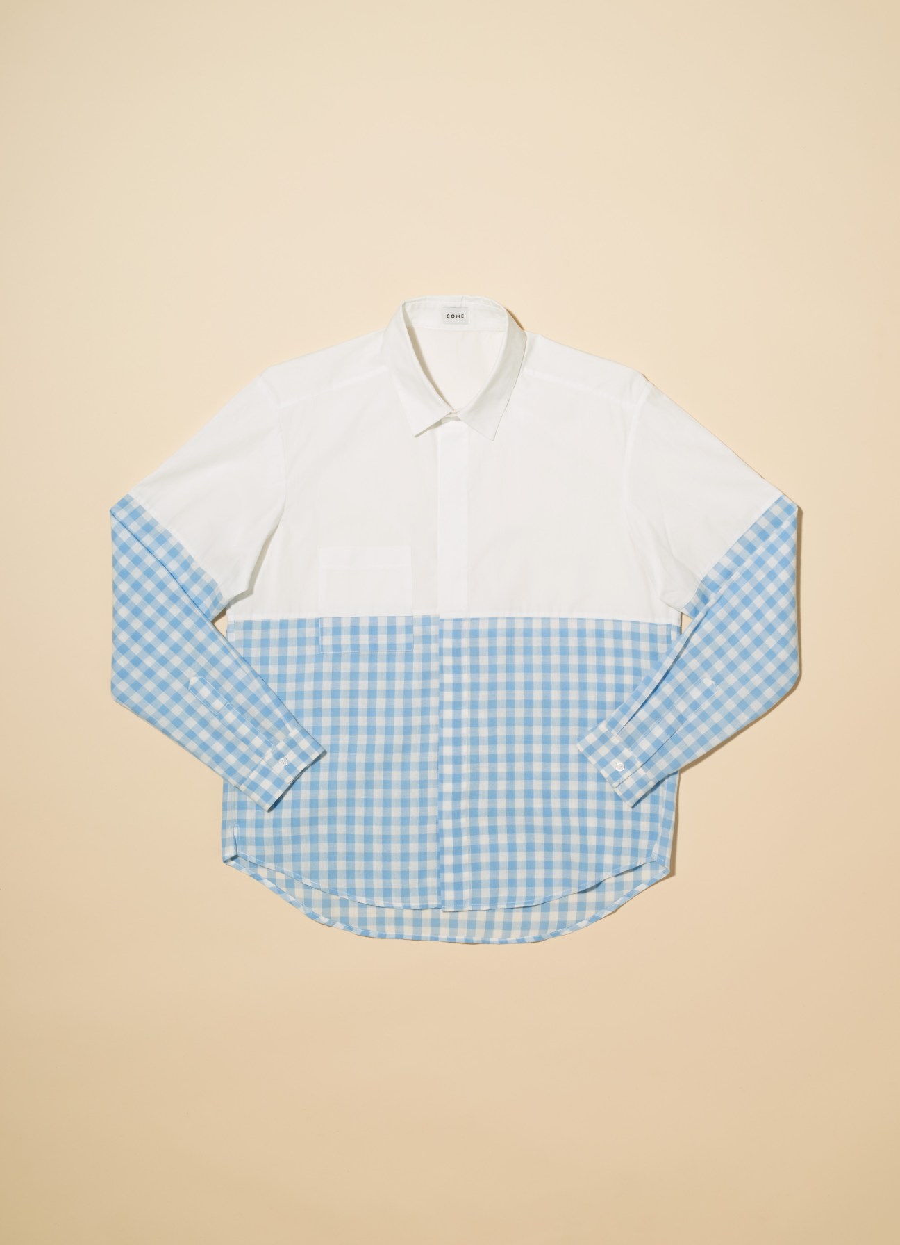 Côme shirt with white upper and light blue gingham lower half on beige background.