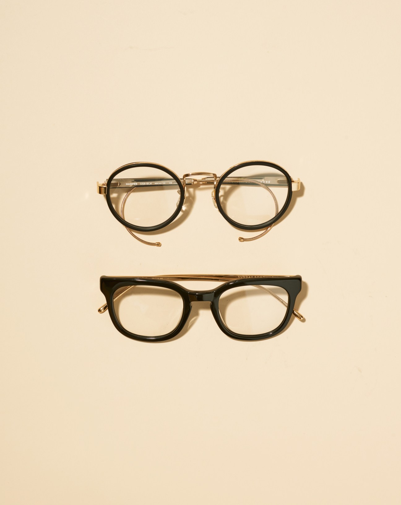 Two pairs of eyeglasses from Sunday Somewhere featuring round frames with thick acetate in black and gold metal details.