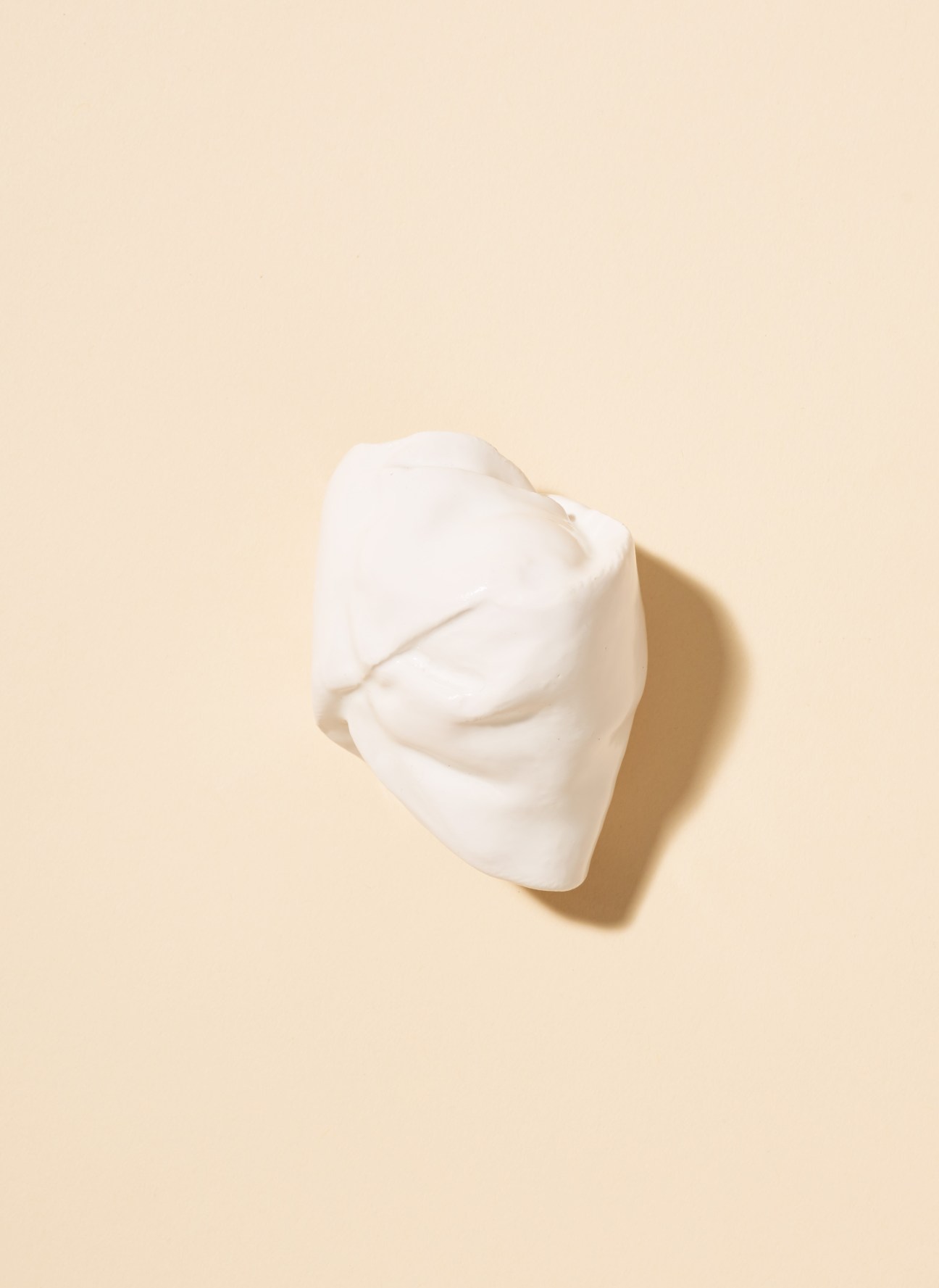 White ceramic knot replica scarf accessory by Heart Heart Heart against a beige background.