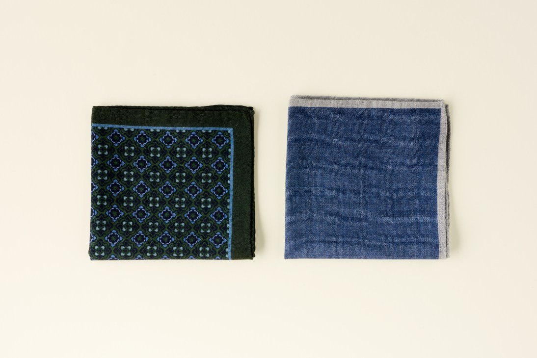 Two folded silk pocket squares by Timothy Everest, one with geometric blue pattern on dark background, one solid blue.