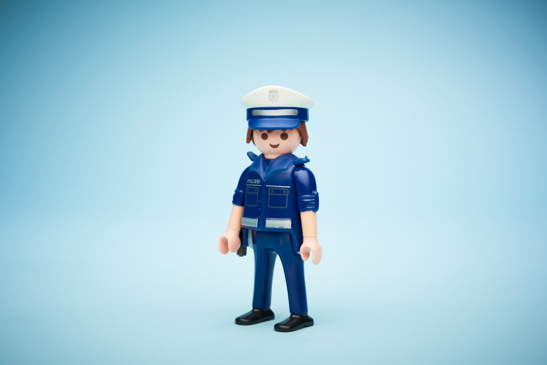 Playmobil police officer figure in blue uniform against a light blue background.