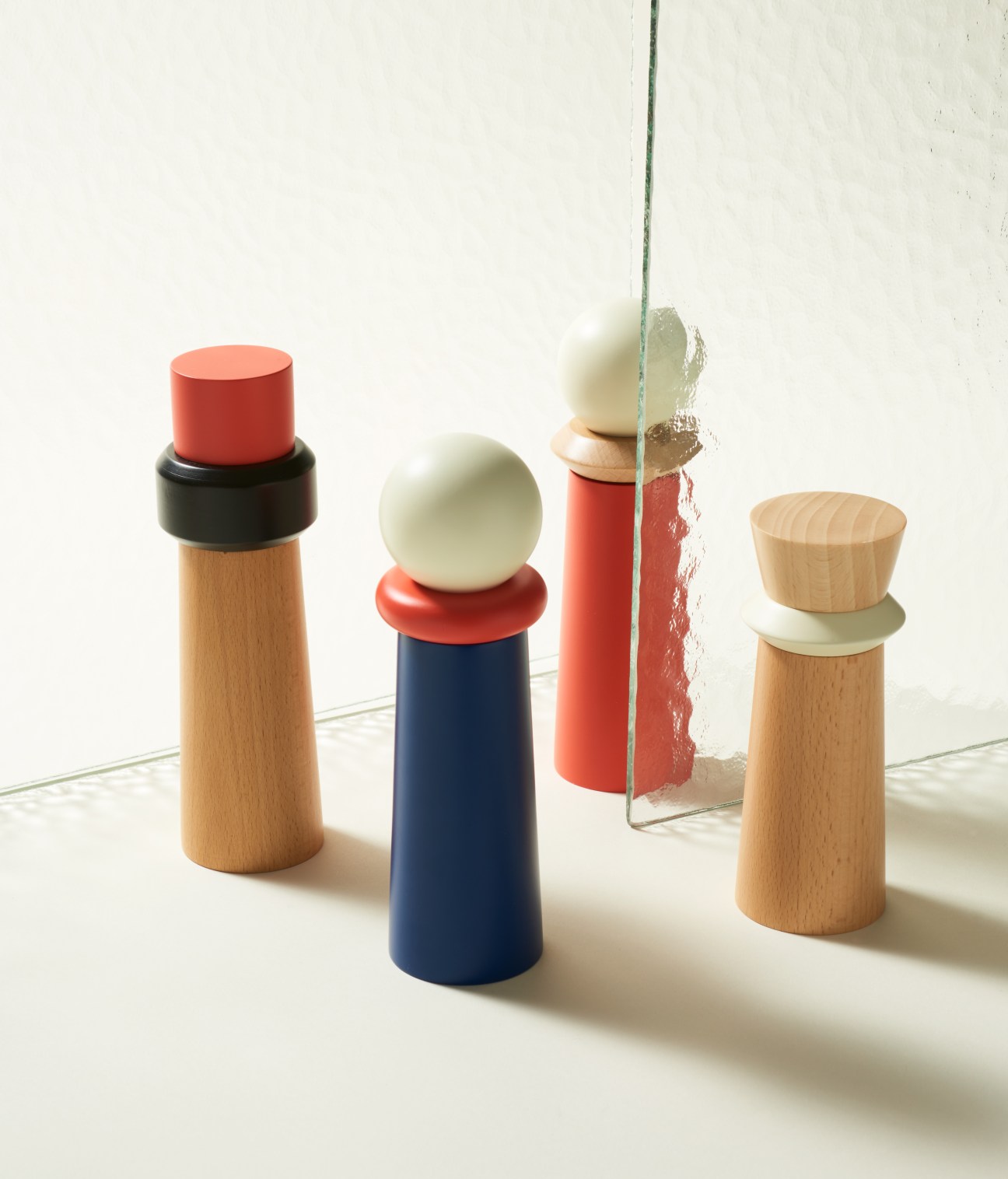 Wooden salt and pepper grinders in the Totem collection by Tylko, featuring modular beech construction with colored ceramic tops in red, navy, and cream.