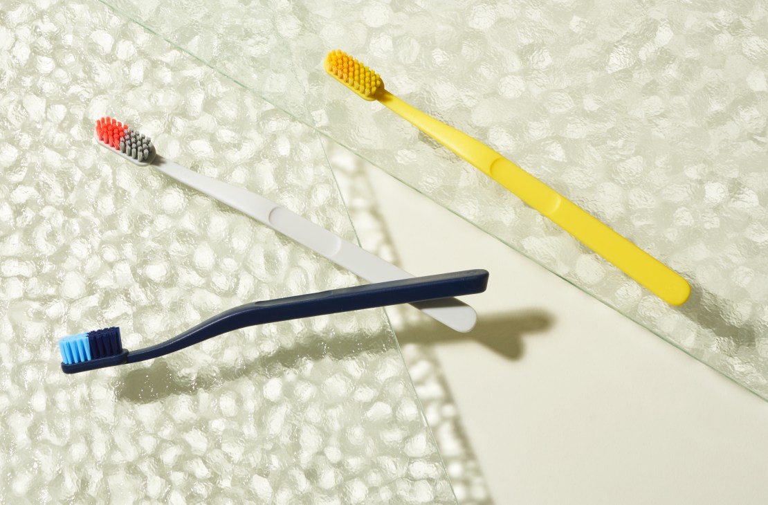 Four colorful toothbrushes with two-tone bristles by Jordan displayed on a textured white surface.