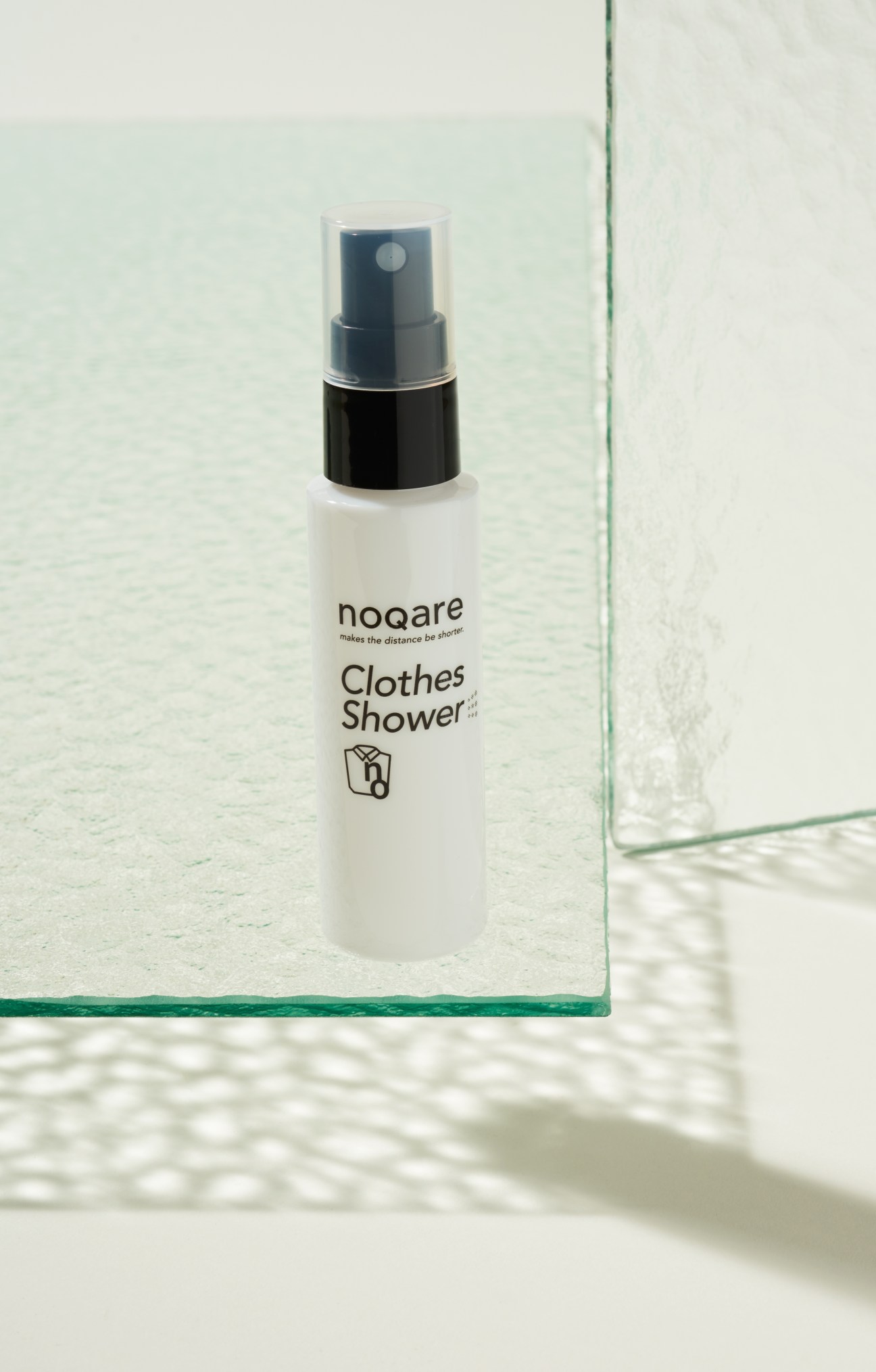 Noqare Clothes Shower spray bottle with black pump dispenser on white surface.