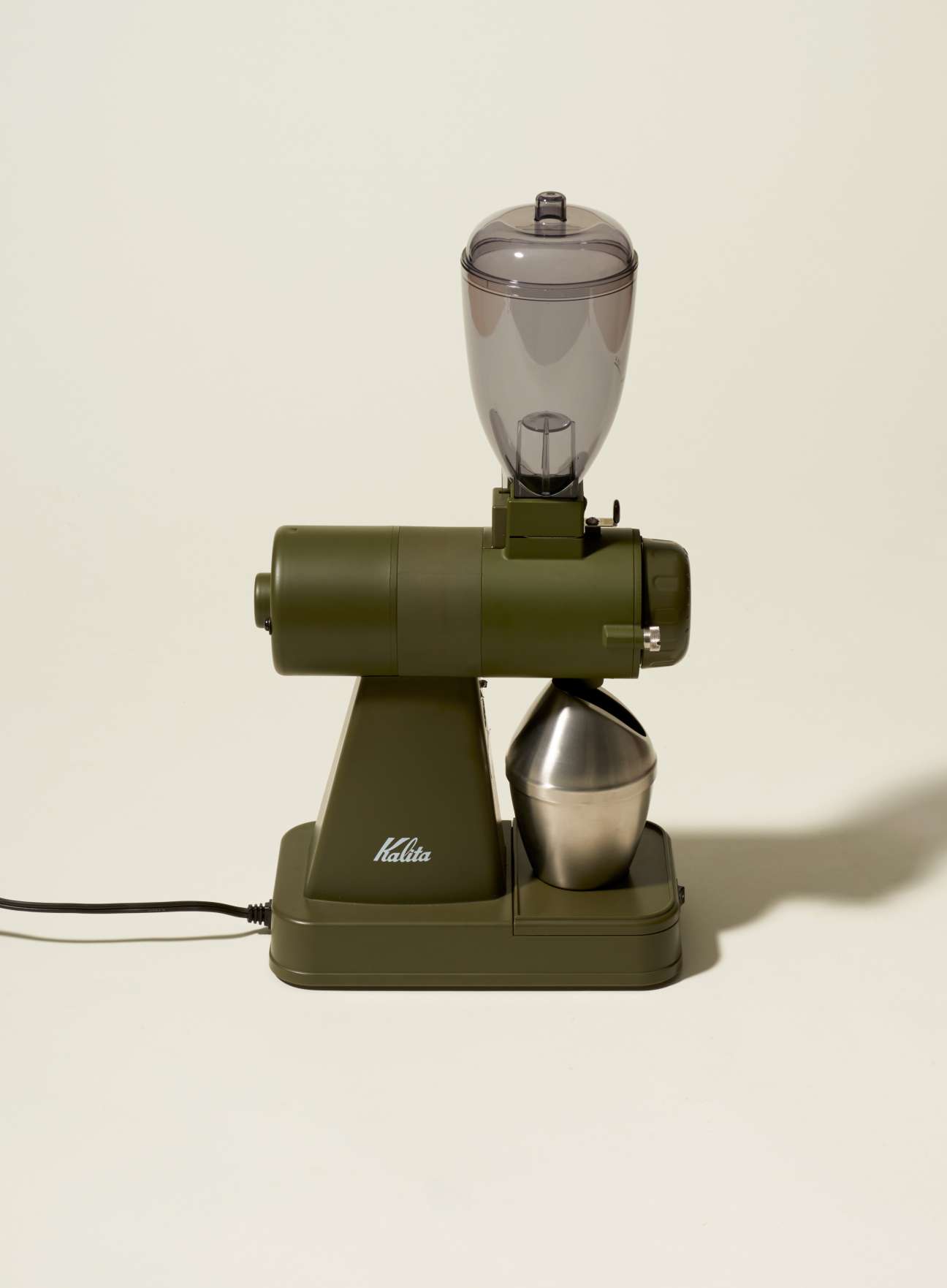 Kalita Japanese coffee grinder in matte khaki with transparent hopper and metal catch cup.